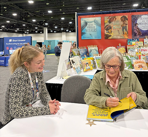 Laurie Lawlor talking with an educator while signing a copy of Many Voices for her